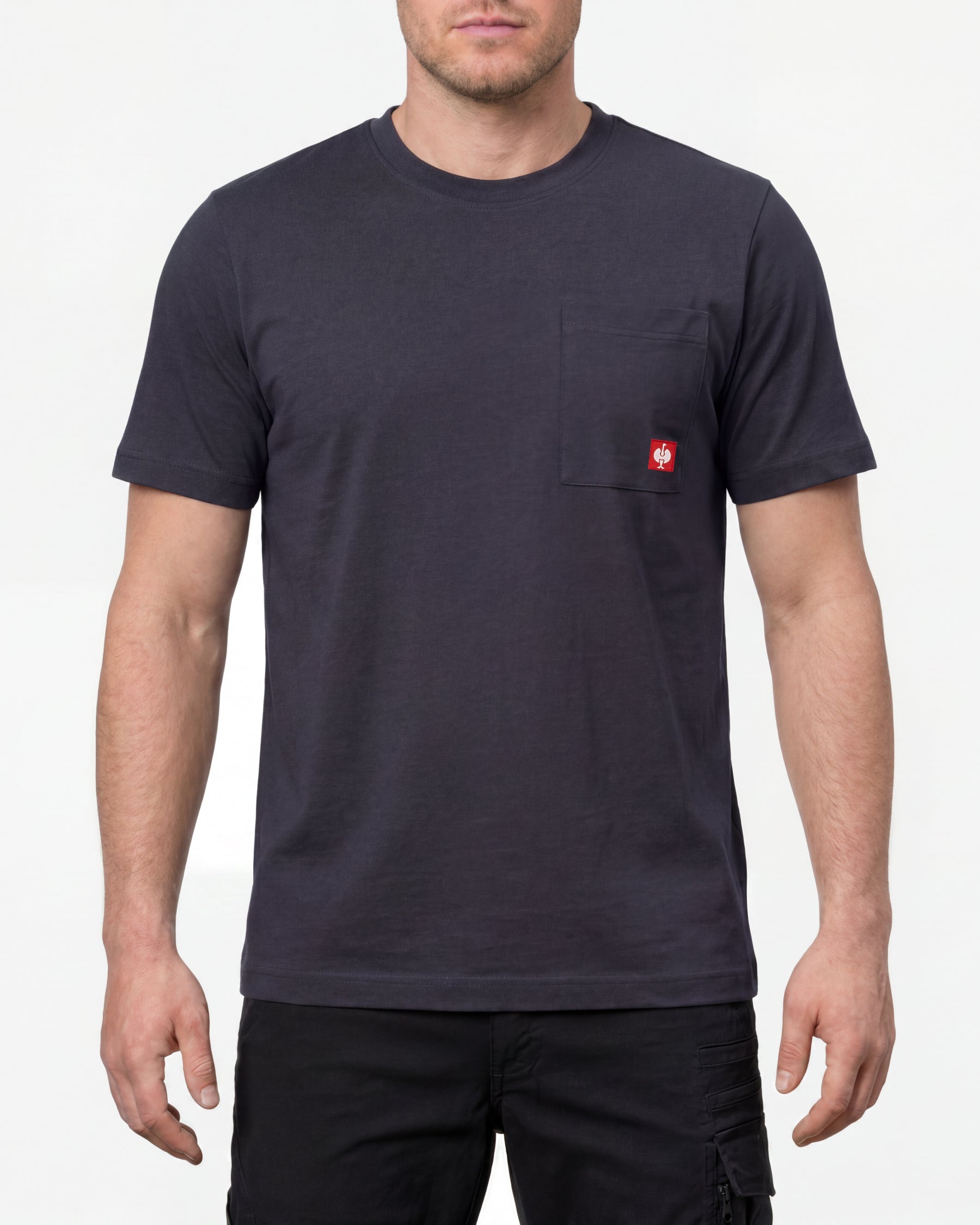 A model wears the STRAUSS Pocket T-Shirt e.s.iconic in nero blue with work pants and work boots in a studio product scene
