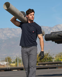 A worker wears the STRAUSS Pocket T-Shirt e.s.iconic in nero blue with work pants on a jobsite