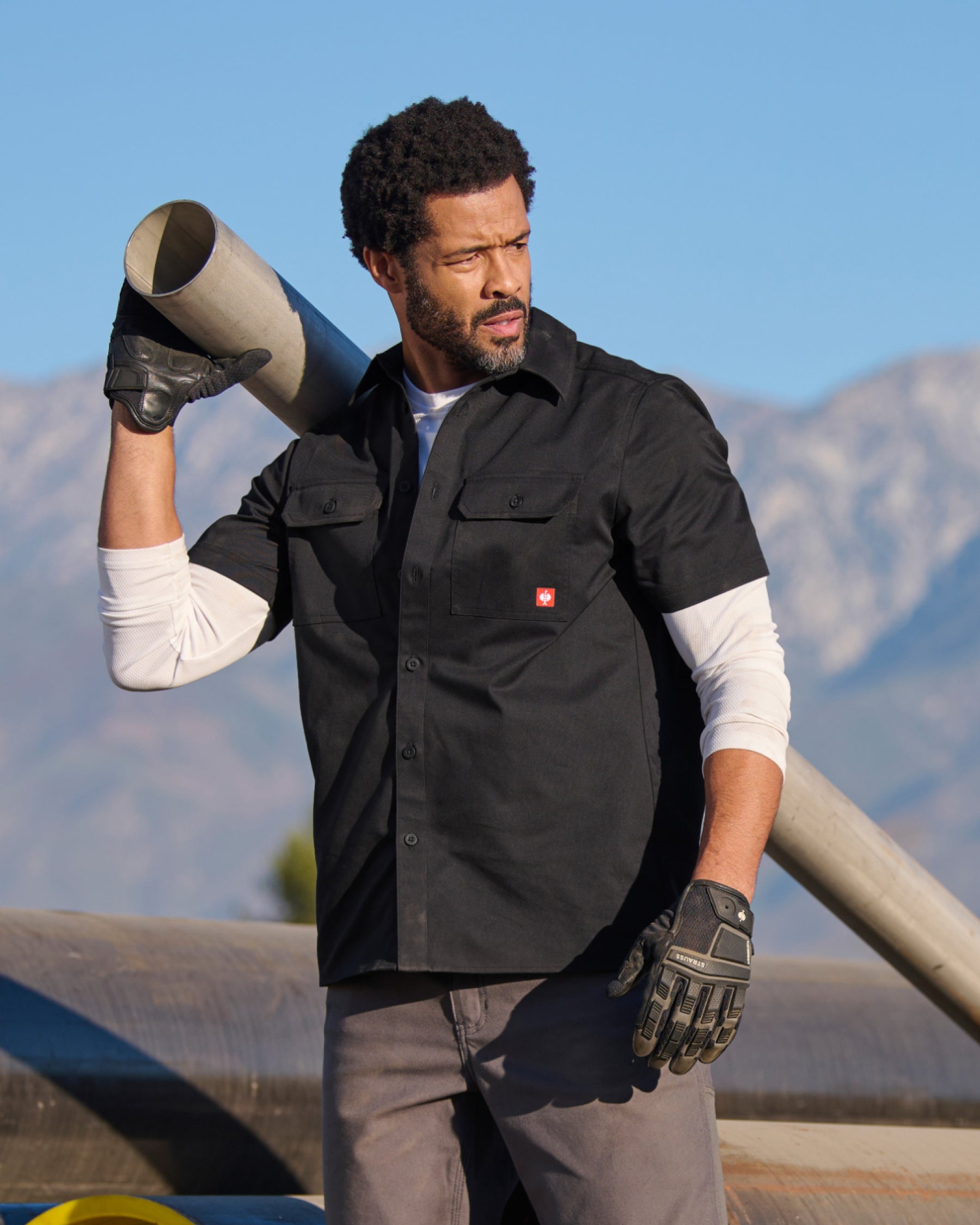 A worker wears the STRAUSS Short Sleeve Work Shirt e.s.iconic in black at a construction site