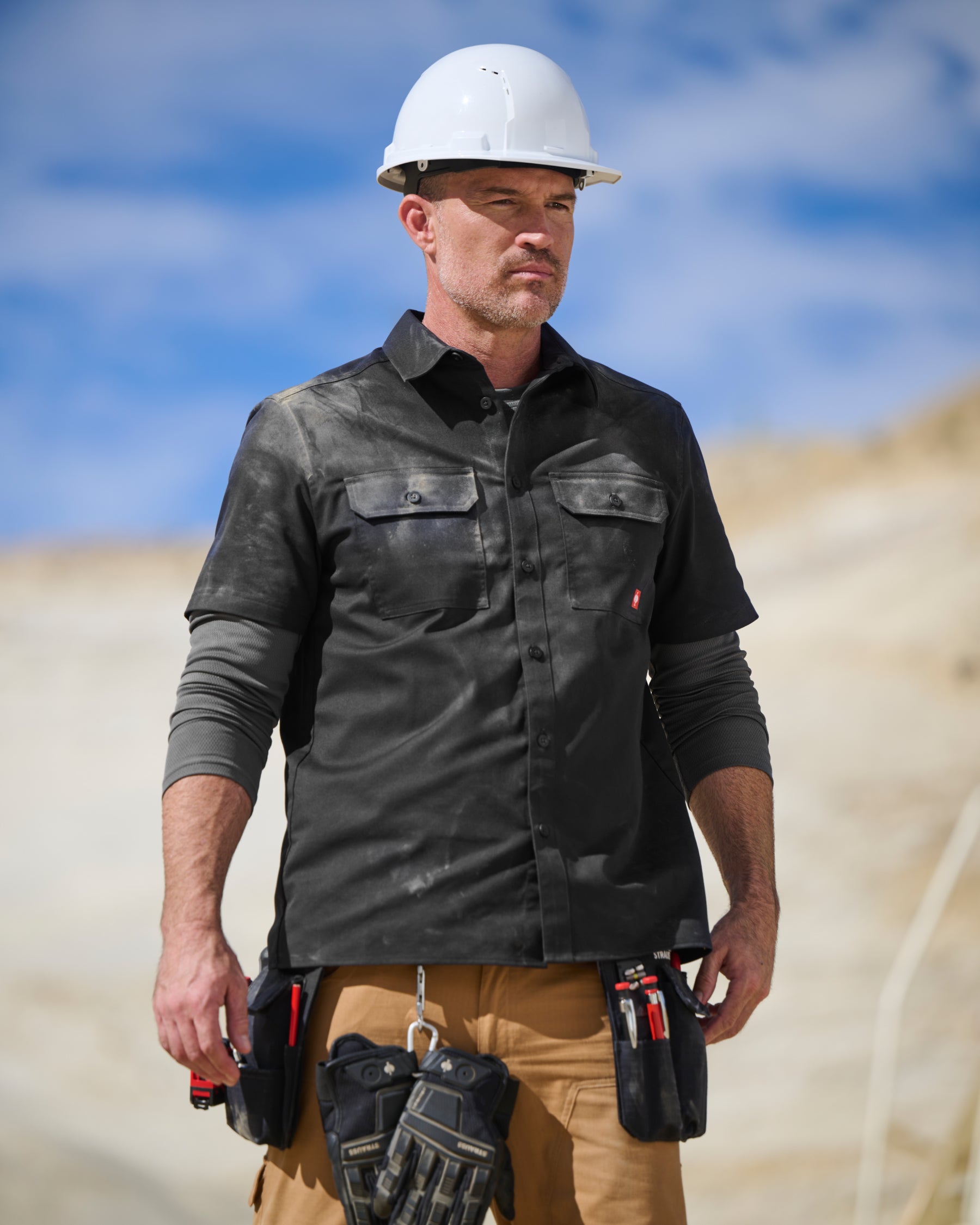 A worker wears the STRAUSS Short Sleeve Work Shirt e.s.iconic in black with work pants