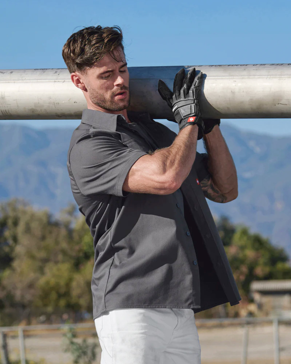 A worker wears the STRAUSS Short Sleeve Work Shirt e.s.iconic in carbon gray with work pants beside construction materials
