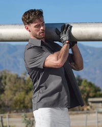 A worker wears the STRAUSS Short Sleeve Work Shirt e.s.iconic in carbon gray with work pants beside construction materials