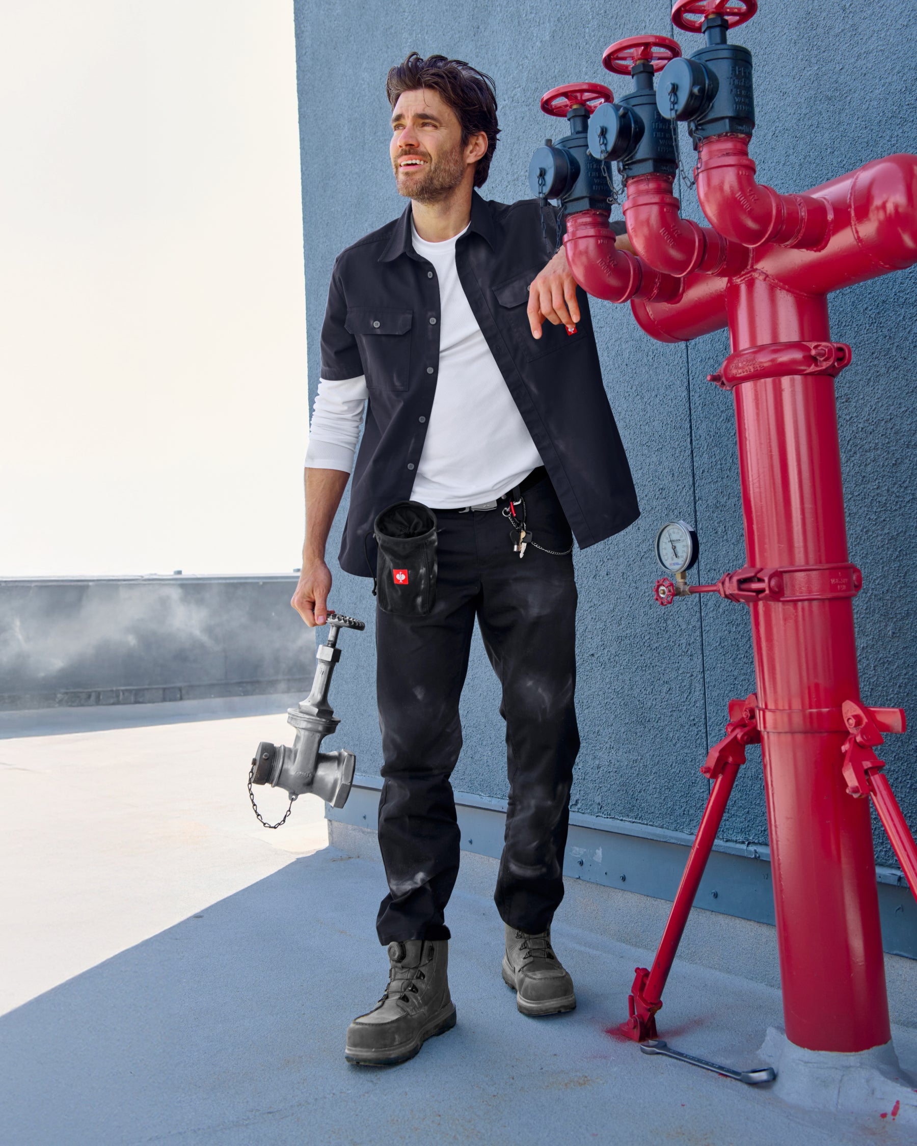A worker wears the STRAUSS Short Sleeve Work Shirt e.s.iconic in nero blue with work pants beside construction materials