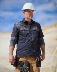 A worker wears the STRAUSS Short Sleeve Work Shirt e.s.iconic in nero blue with work pants outside a shop entrance