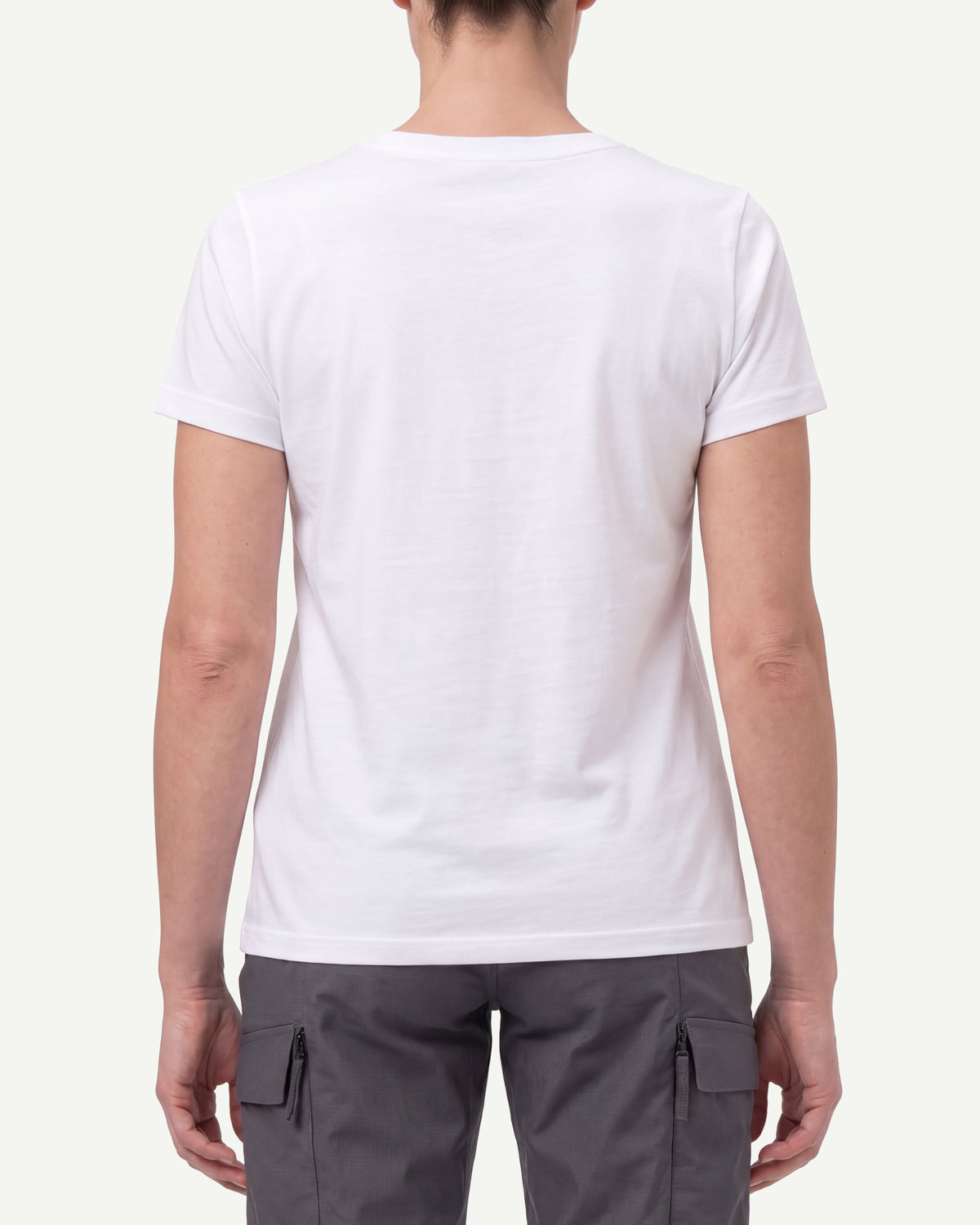 A woman wears the Women's STRAUSS Cotton Stretch T-Shirt in white with work pants and work boots, showing the shirt fit