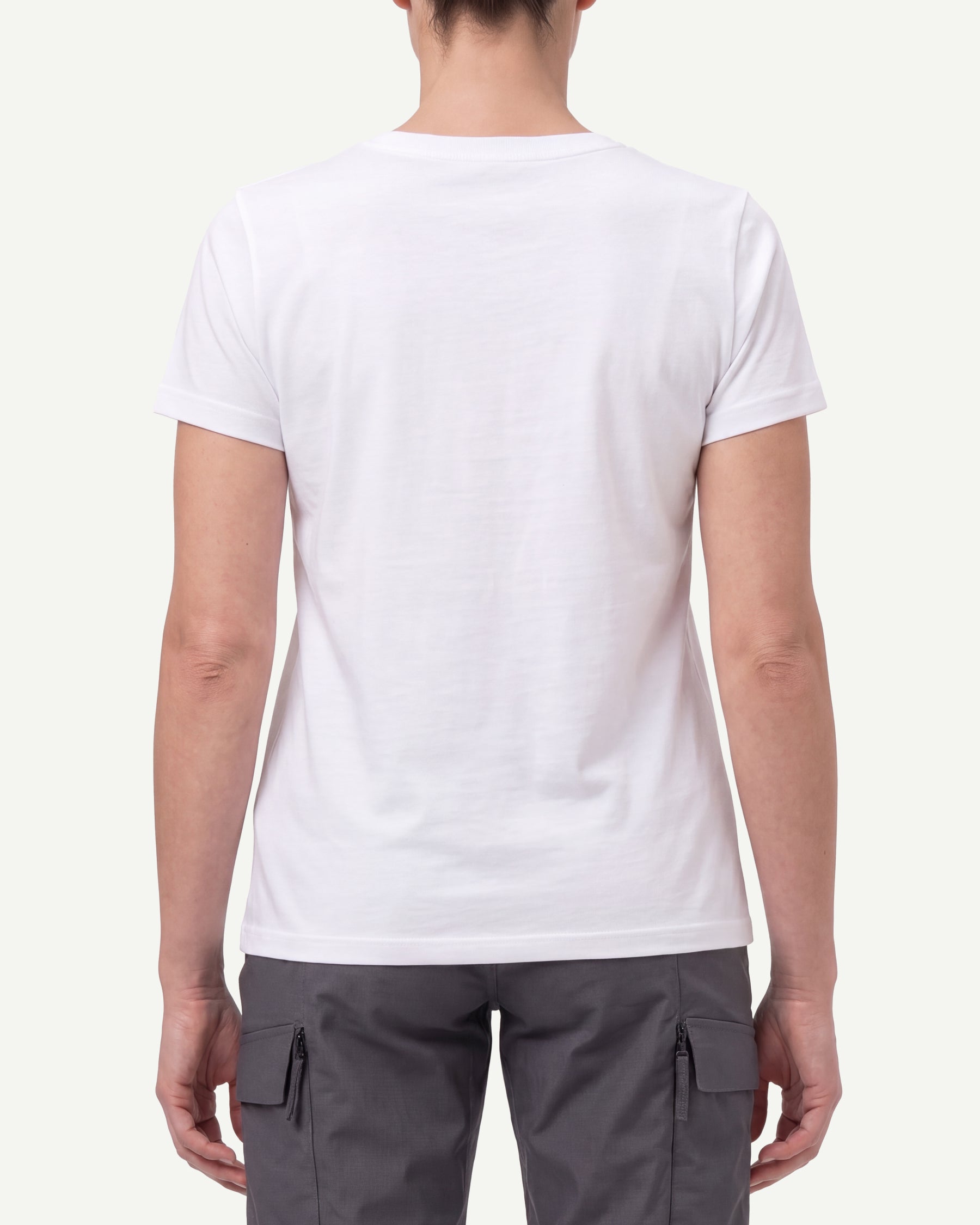 A woman wears the Women's STRAUSS Cotton Stretch T-Shirt in white with work pants and work boots, showing the shirt fit
