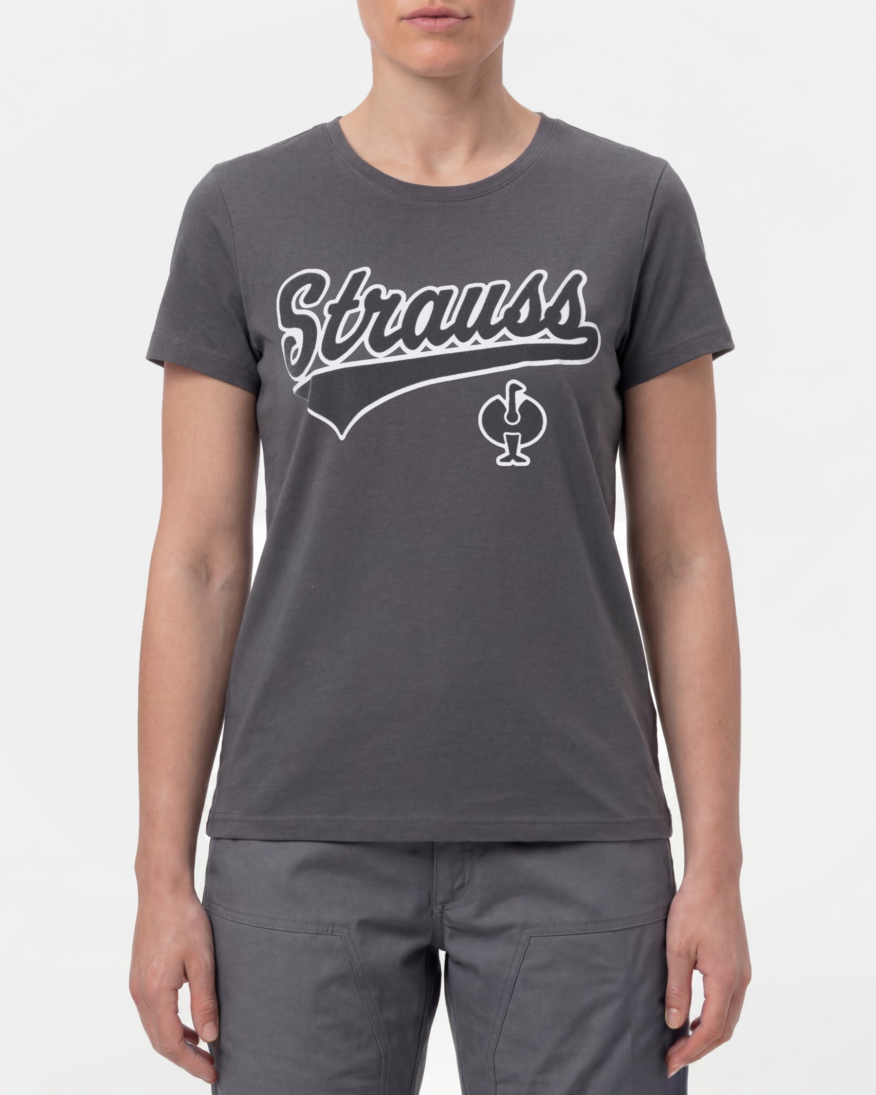 A woman wears the Women's STRAUSS Artwork T-Shirt e.s.e:pic in carbon gray with work pants and work boots in a studio product scene