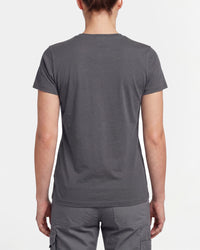A woman wears the Women's STRAUSS Artwork T-Shirt e.s.e:pic in carbon gray with work pants and work boots, showing the shirt fit