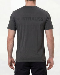 A model wears the STRAUSS Seamless Tee e.s.trail pure in black melange with work gloves and work pants, showing the shirt fit