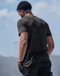 A model wears the STRAUSS Seamless Tee e.s.trail pure in black melange with work pants under direct sun