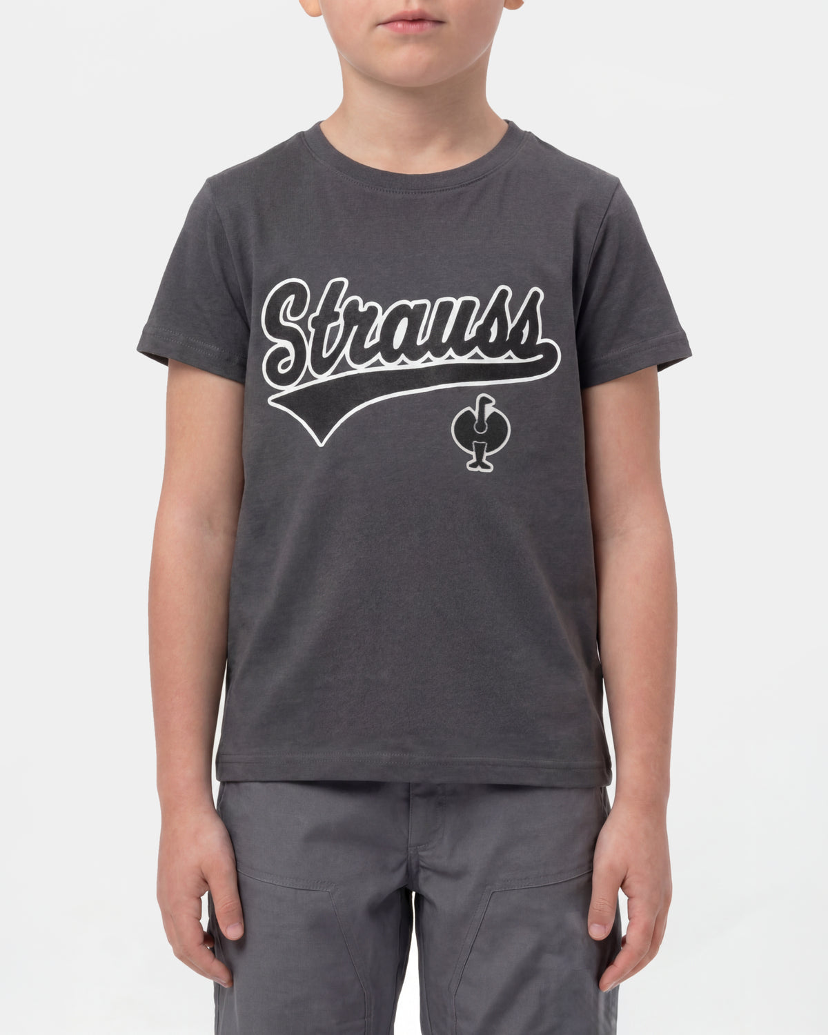 A child wears the Kids' STRAUSS Artwork T-Shirt e.s.e:pic in carbon gray with casual workwear pants in a studio product scene