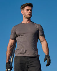 A worker wears the STRAUSS Cotton Stretch T-Shirt in carbon gray on a sunny jobsite