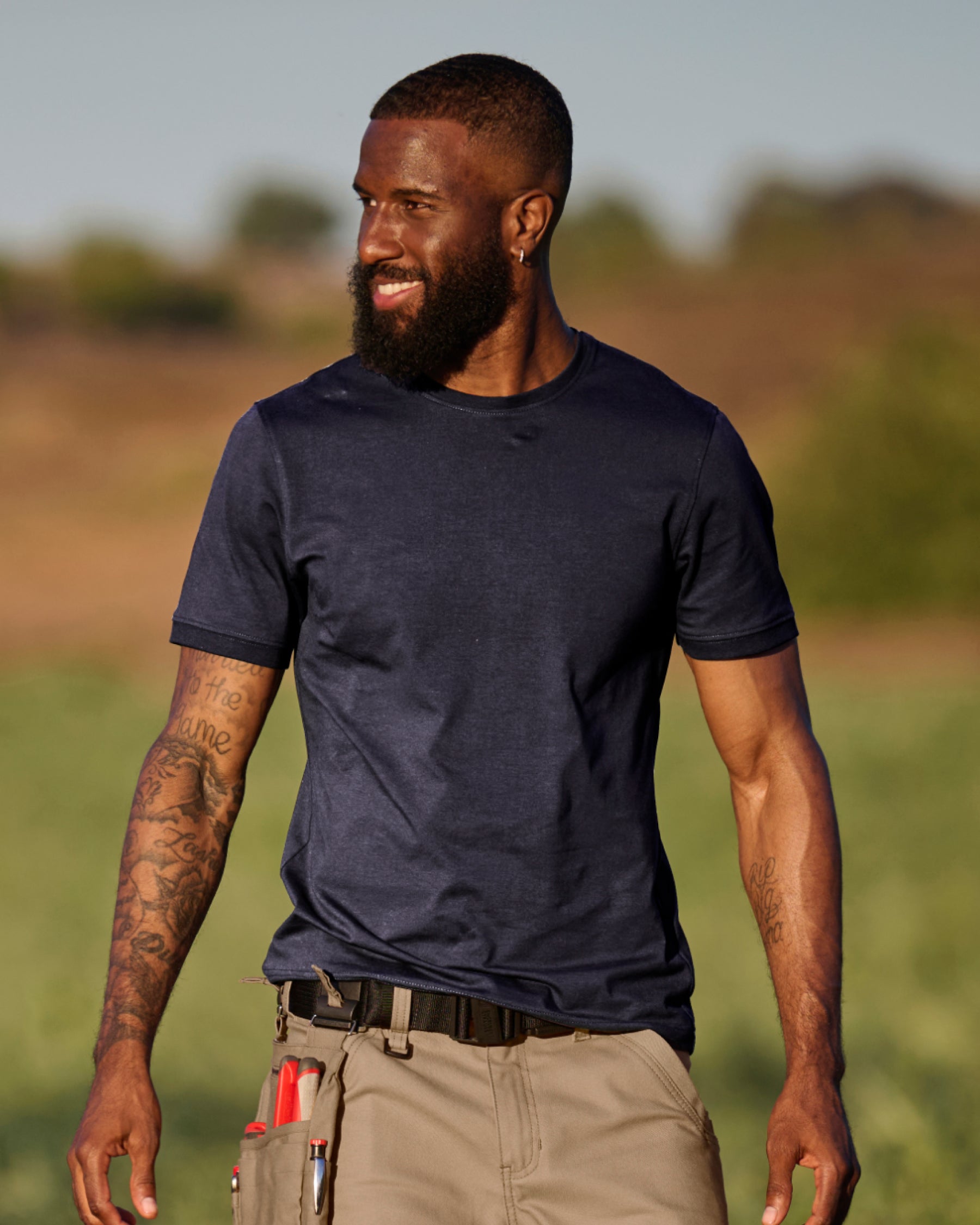 A worker wears the STRAUSS Cotton Stretch T-Shirt in nero blue with on a sunny jobsite