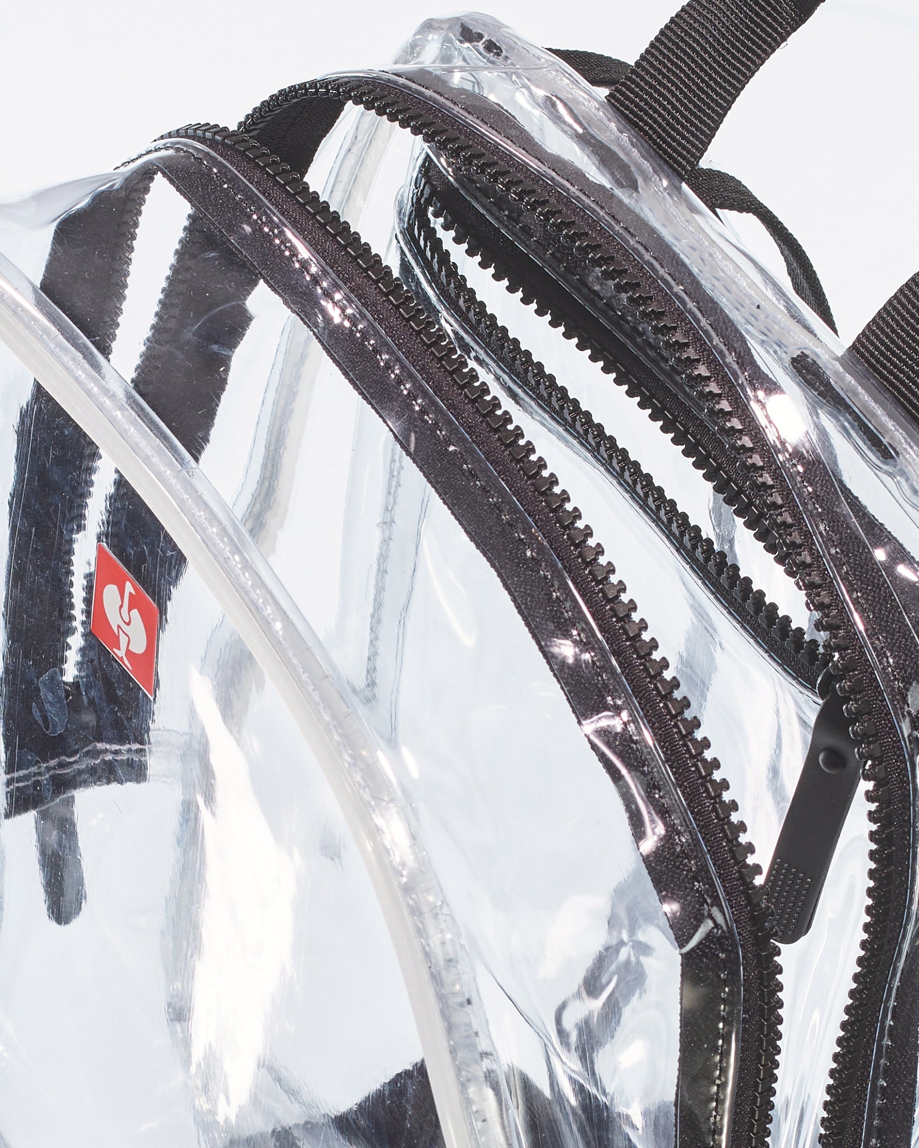 Close-up of the transparent panel, zipper, and strap on the clear STRAUSS e.s.e:pic backpack.