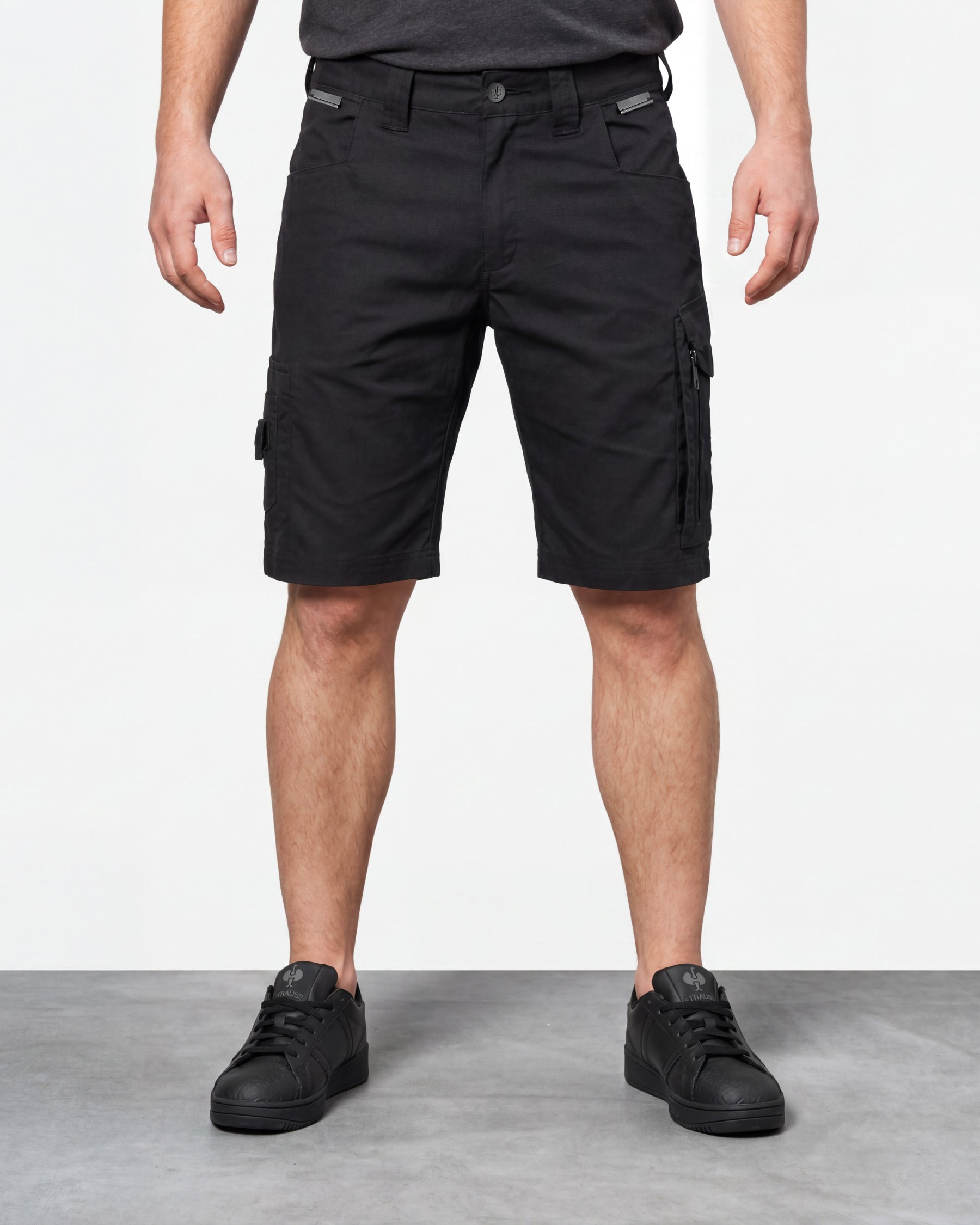 Model wearing Engelbert Strauss e.s. concrete light shorts in black, showing the fit, length, waistband, and front pocket layout of the lightweight work shorts with a practical pocket layout.