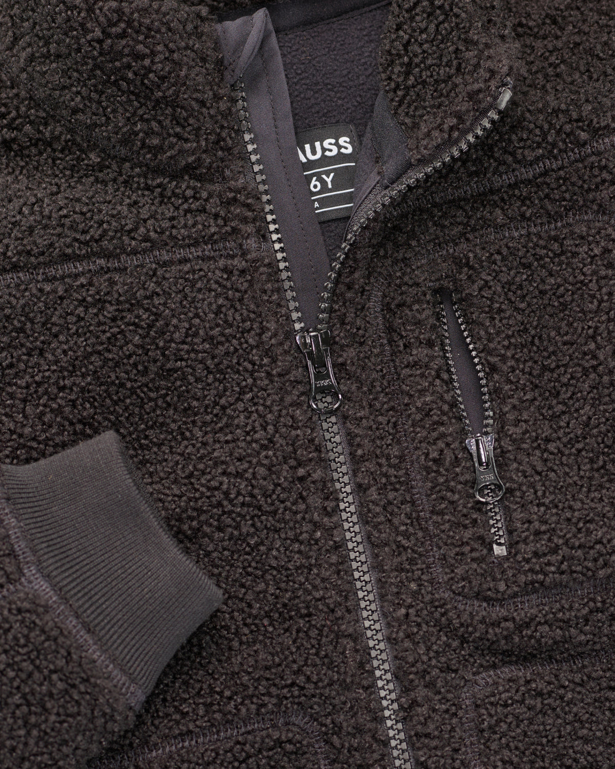 Close-up of sherpa fleece texture and collar details on STRAUSS kids' e.s.e:pic sherpa fleece jacket in black