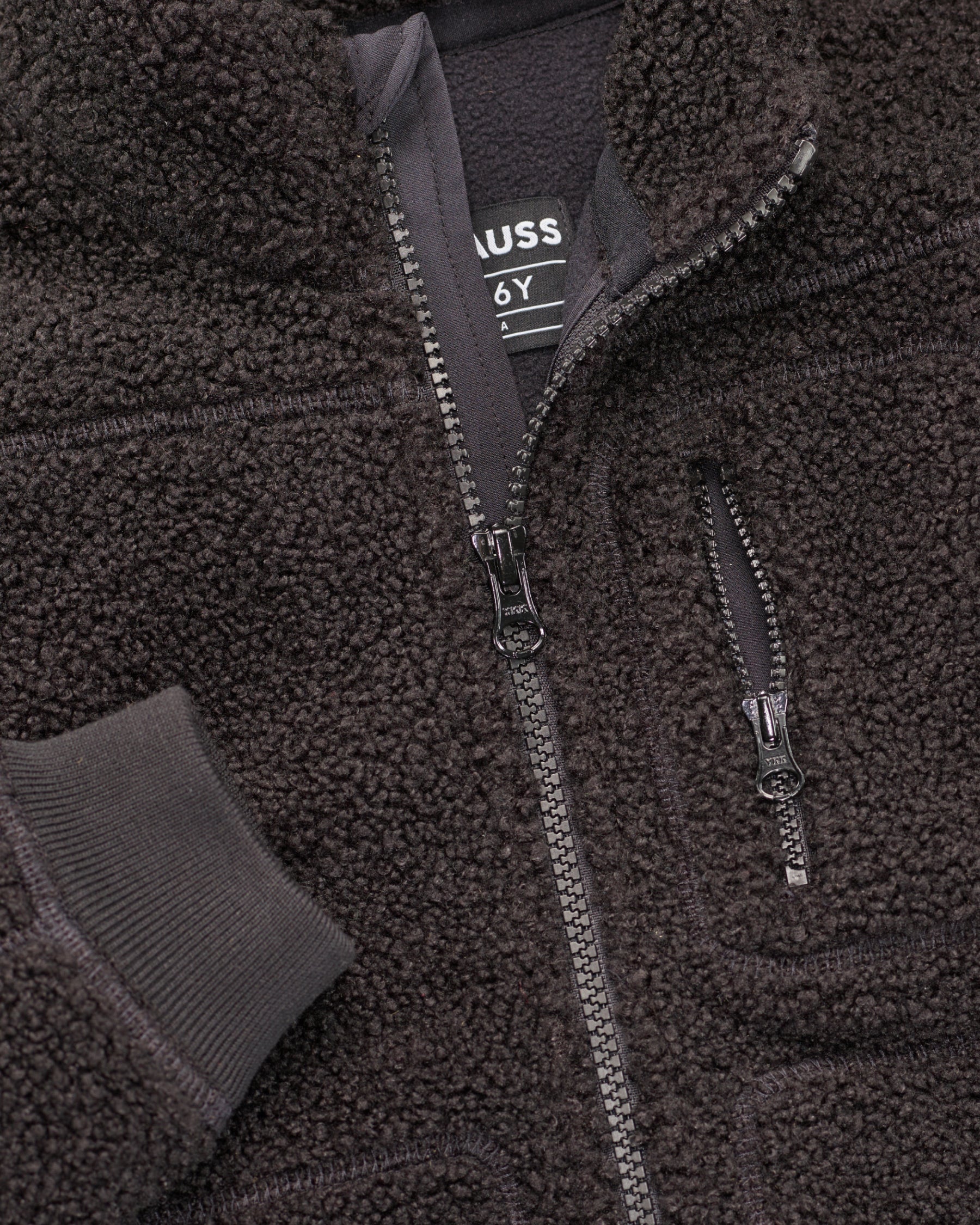 Close-up of sherpa fleece texture and collar details on STRAUSS kids' e.s.e:pic sherpa fleece jacket in black