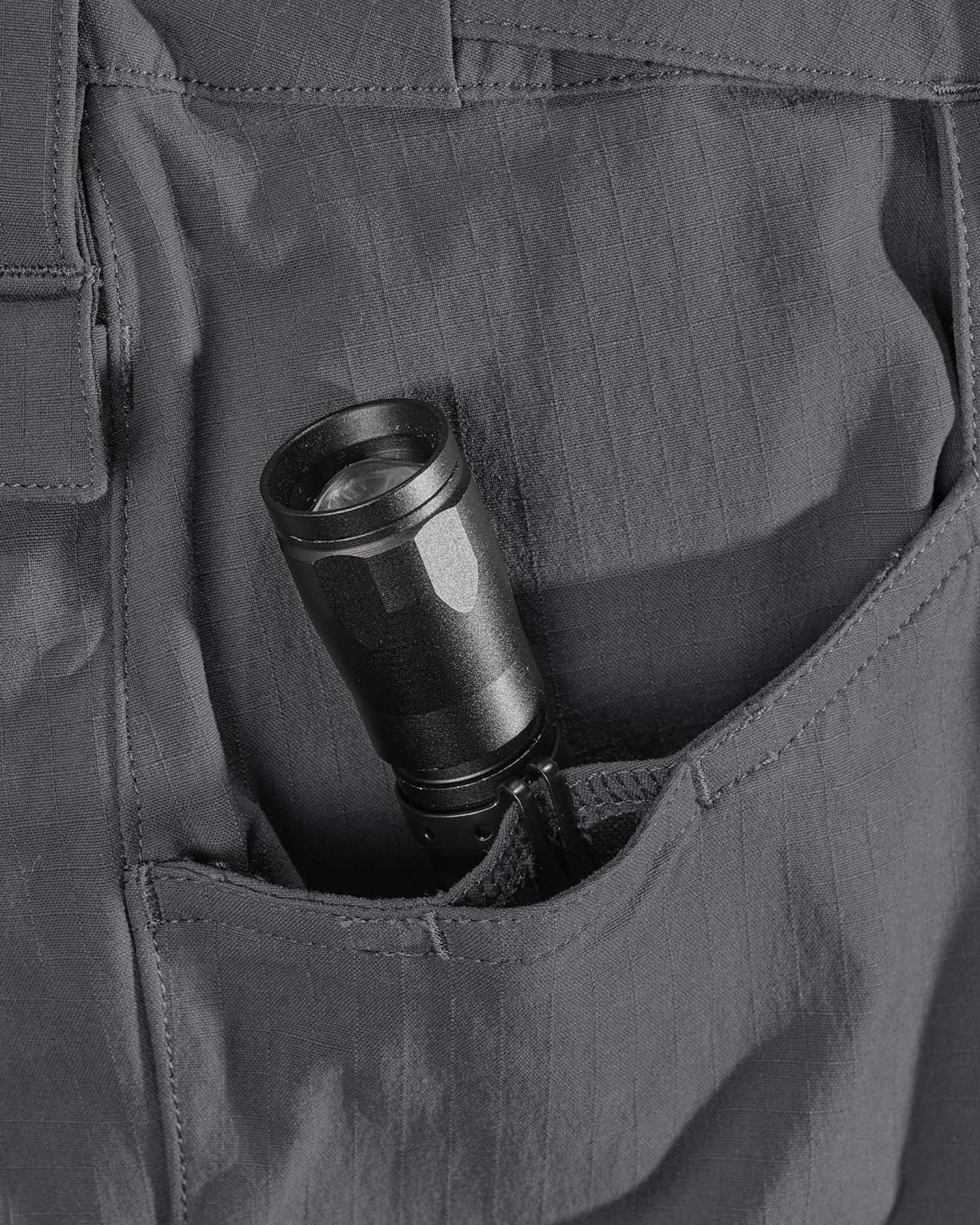 Close-up detail of Engelbert Strauss e.s. taktik stretch ripstop cargo work shorts in carbon gray, focusing on the utility pocket area, seams, and reinforced workwear construction.
