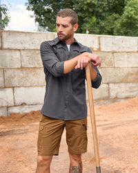 Engelbert Strauss e.s. taktik stretch ripstop cargo work shorts in desert brown in an outdoor-style lifestyle view, showing the shorts as part of a functional work outfit.