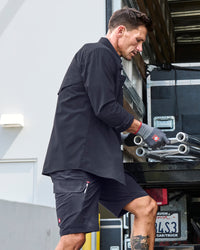 Engelbert Strauss e.s. taktik stretch ripstop cargo work shorts in nero blue in a lifestyle action view, highlighting the practical pocket access and durable workwear silhouette.