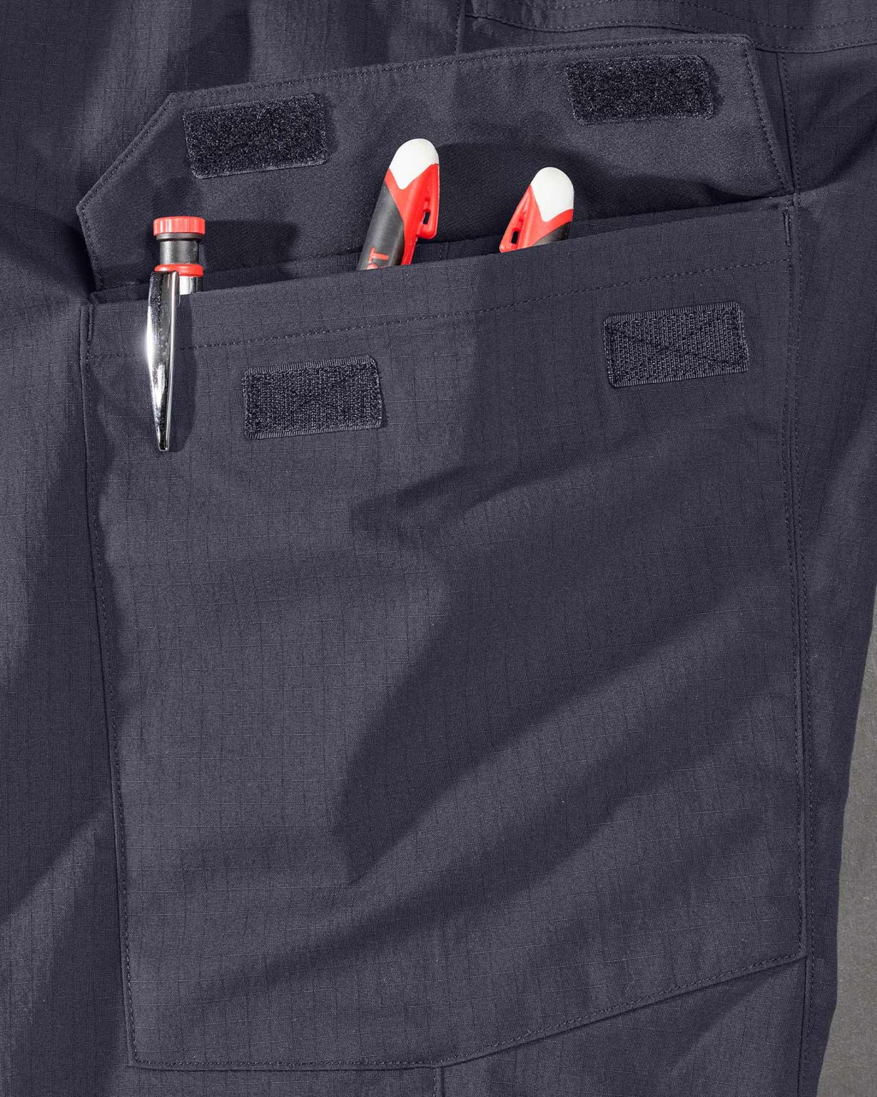 Close-up detail of Engelbert Strauss e.s. taktik stretch ripstop cargo work shorts in nero blue, focusing on the utility pocket area, seams, and reinforced workwear construction.