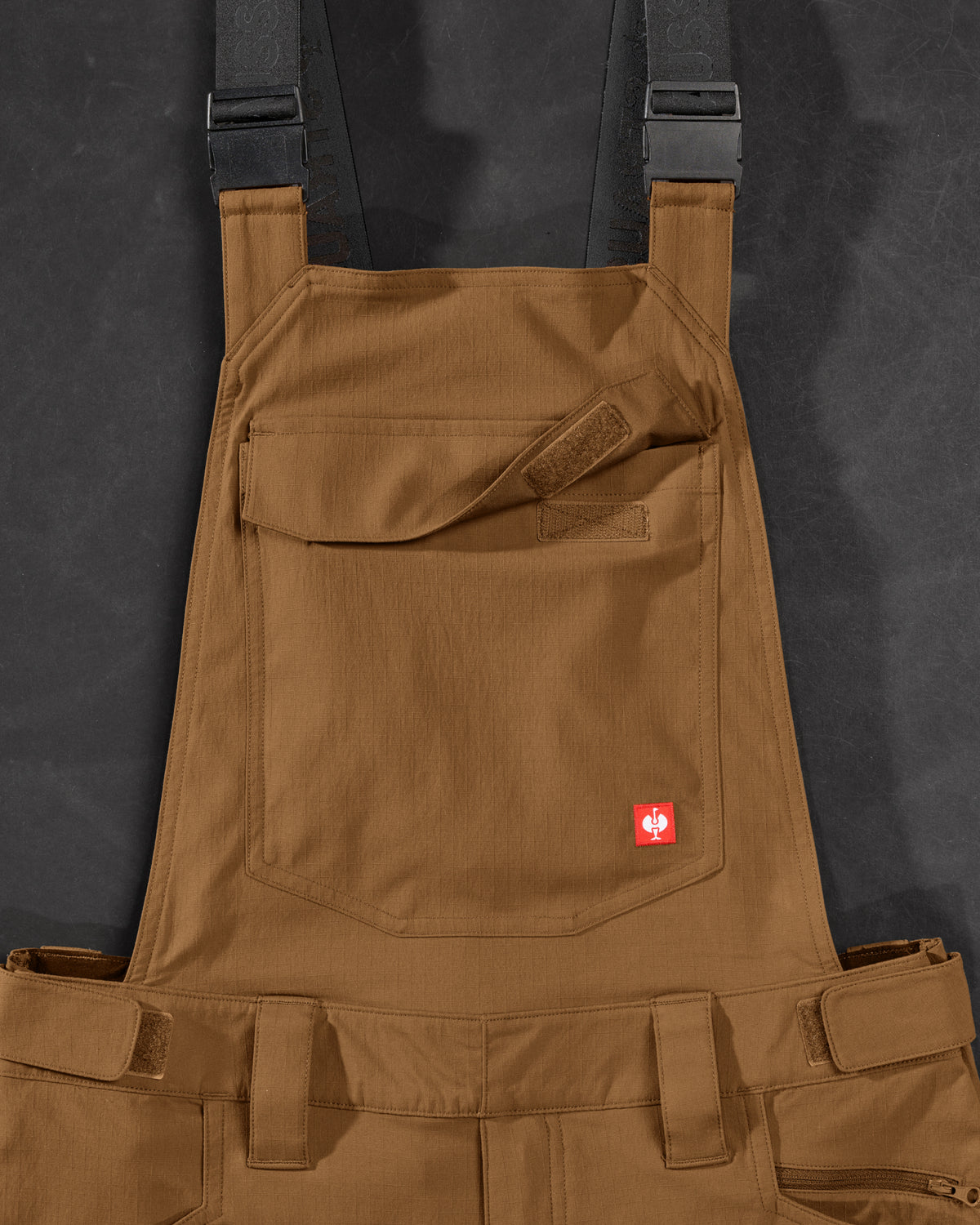 Close-up of desert brown STRAUSS Stretch Ripstop Cargo Work Bib Overall e.s.taktik seam, hardware, and workwear details