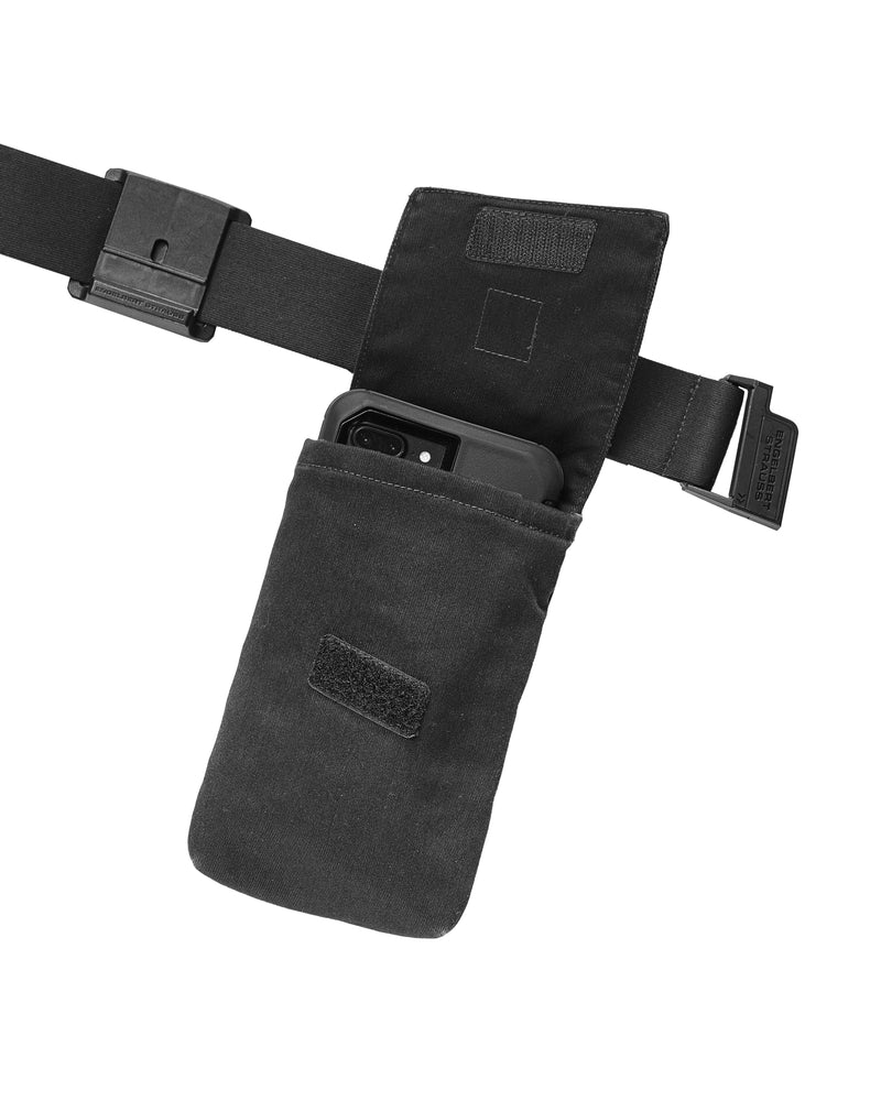 A worker wears a oxid black STRAUSS e.s.motion ten mobile phone pocket attached to work pants beside other tool pockets.
