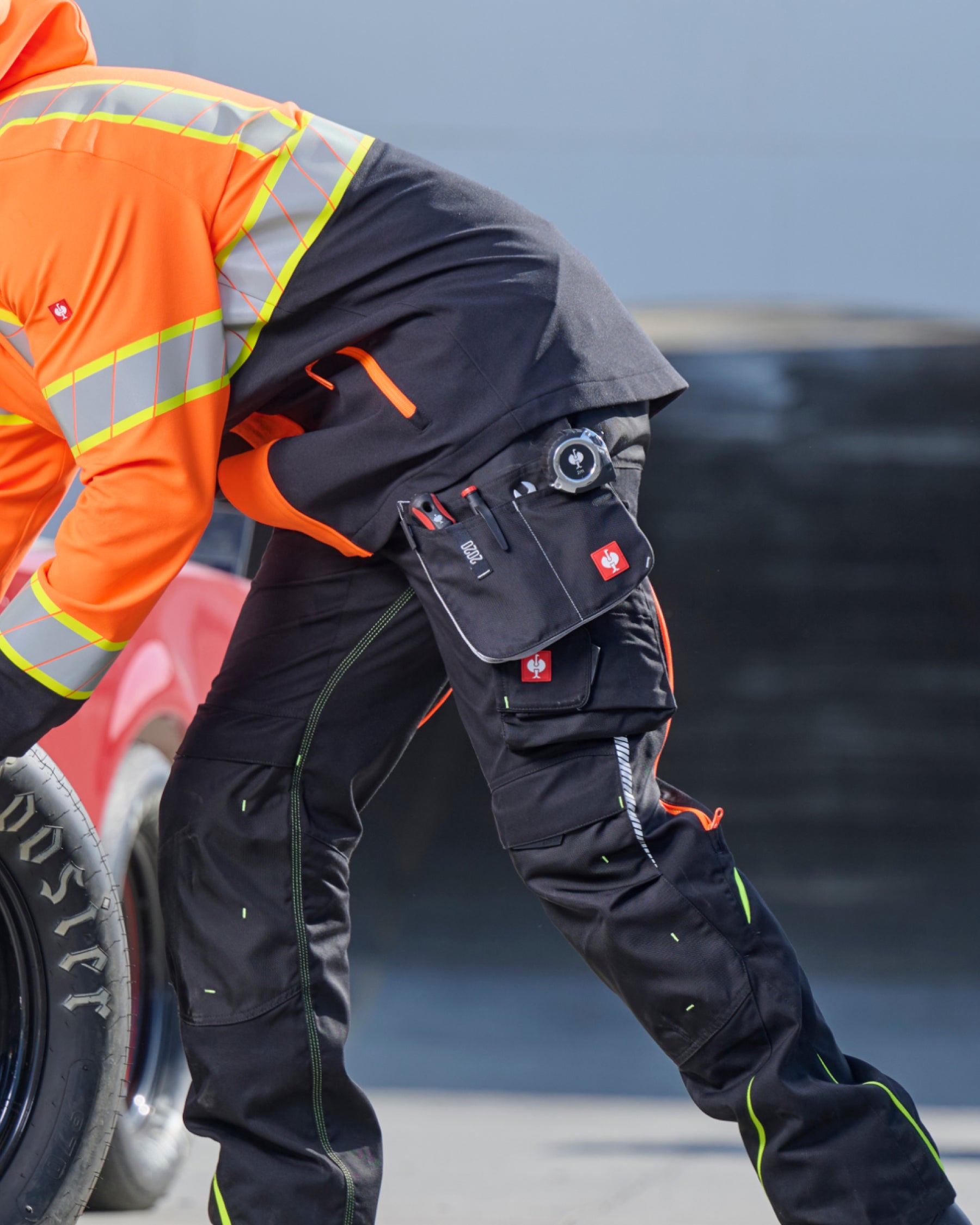 A worker in STRAUSS work pants uses a black and platinum e.s.motion 2020 large tool bag for tools at a jobsite.