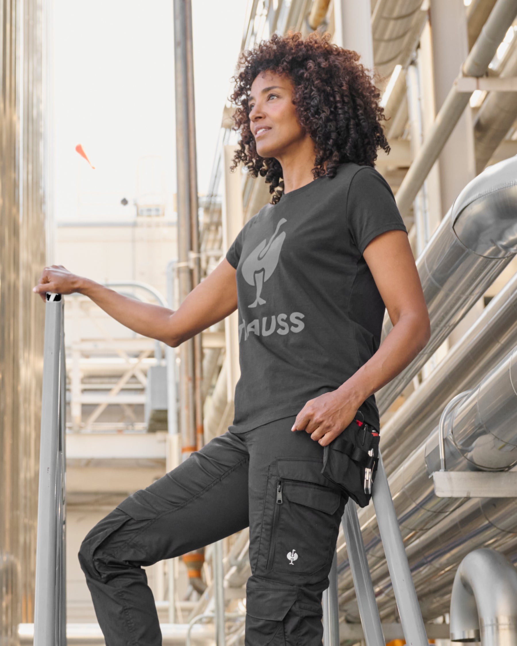 A black STRAUSS women's e.s.concrete light tool bags is fastened to work pants while a worker reaches for hand tools.