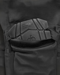 Close-up of dark gray protective knee pad and a black velcro strap on tactical pants.