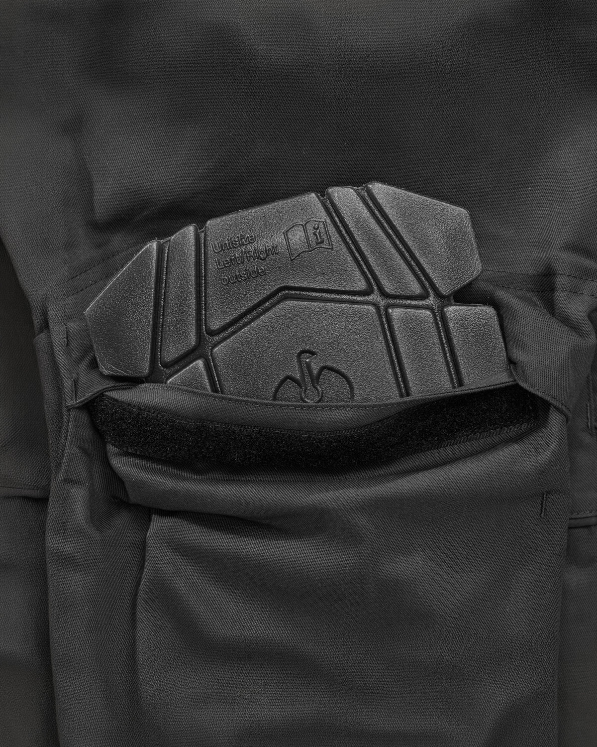 Close-up of dark gray protective knee pad and a black velcro strap on tactical pants.