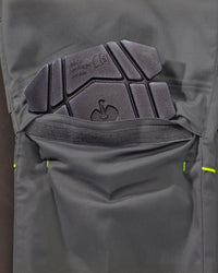 Close-up of a dark gray technical knee pad pocket showing a built-in protective pad with molded text and logo embossing.