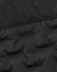 Close-up of a black quilted puffer jacket fabric showing the stitched panel construction.