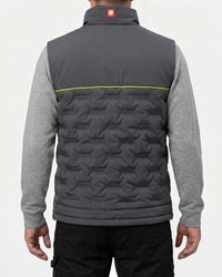 A man viewed from the back wearing a dark gray quilted vest over a heather gray long-sleeve shirt and black pants. The vest features a geometric star pattern, a high collar, and a thin yellow horizontal stripe across the upper back.