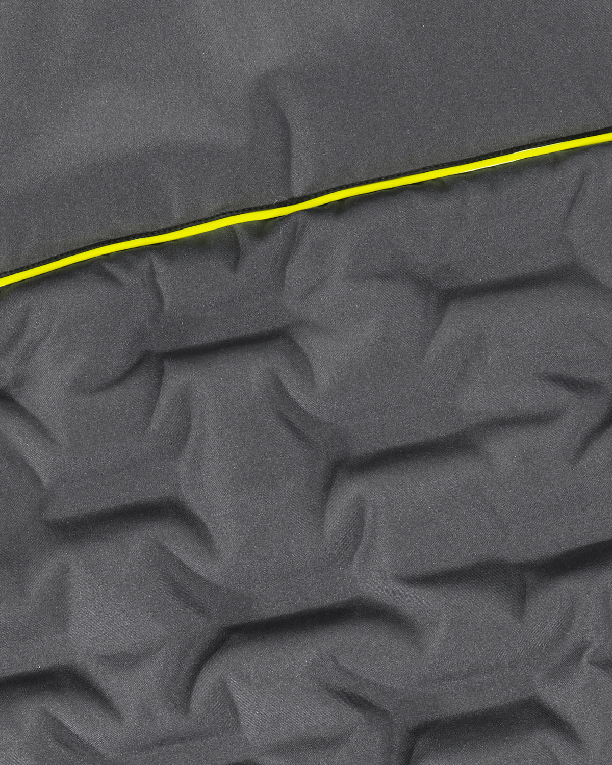 Close-up of dark gray quilted fabric with a bright yellow stitched line running diagonally across the surface.