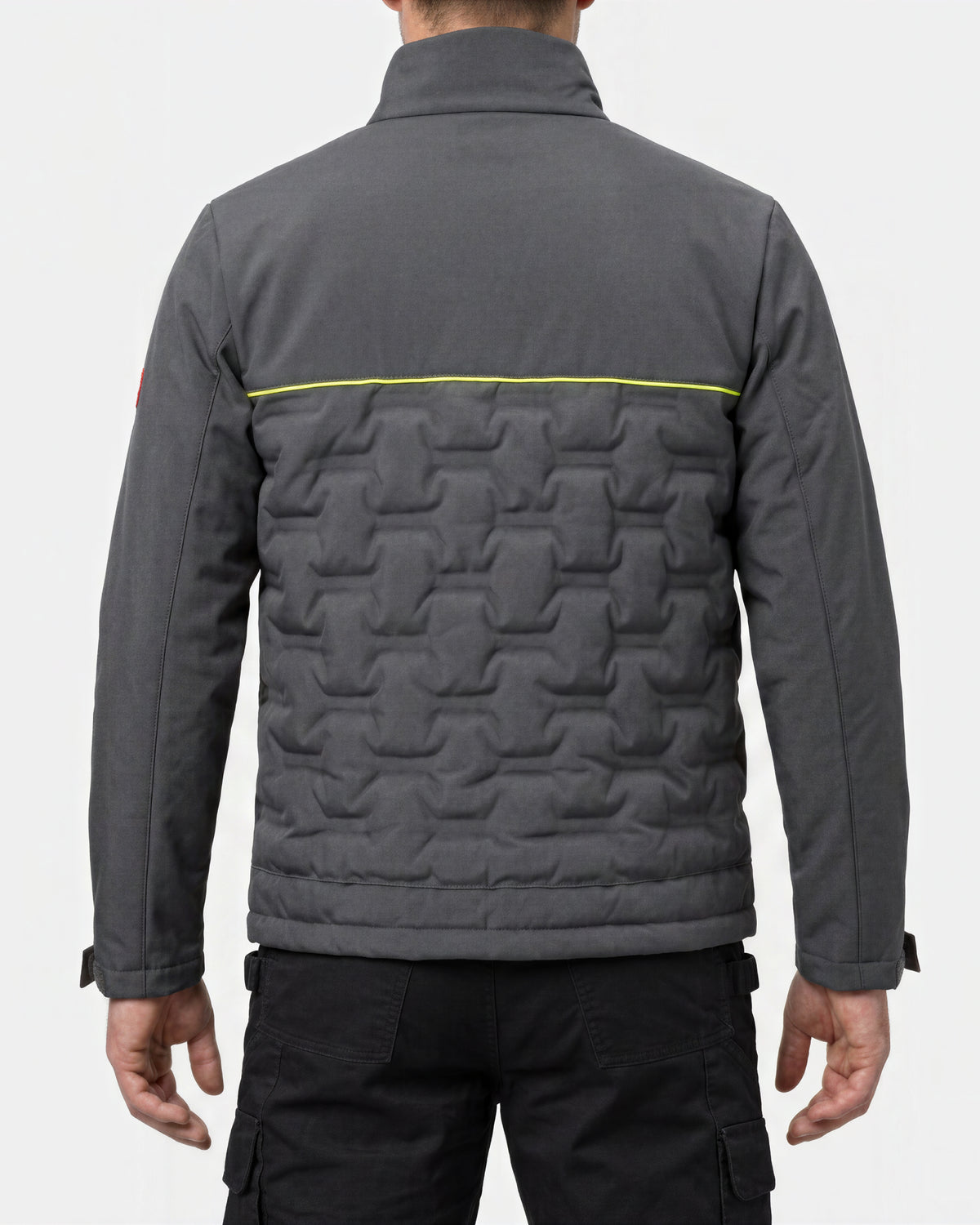 Back view of a dark gray quilted jacket with a bright yellow horizontal stripe across the upper back, worn by a model.