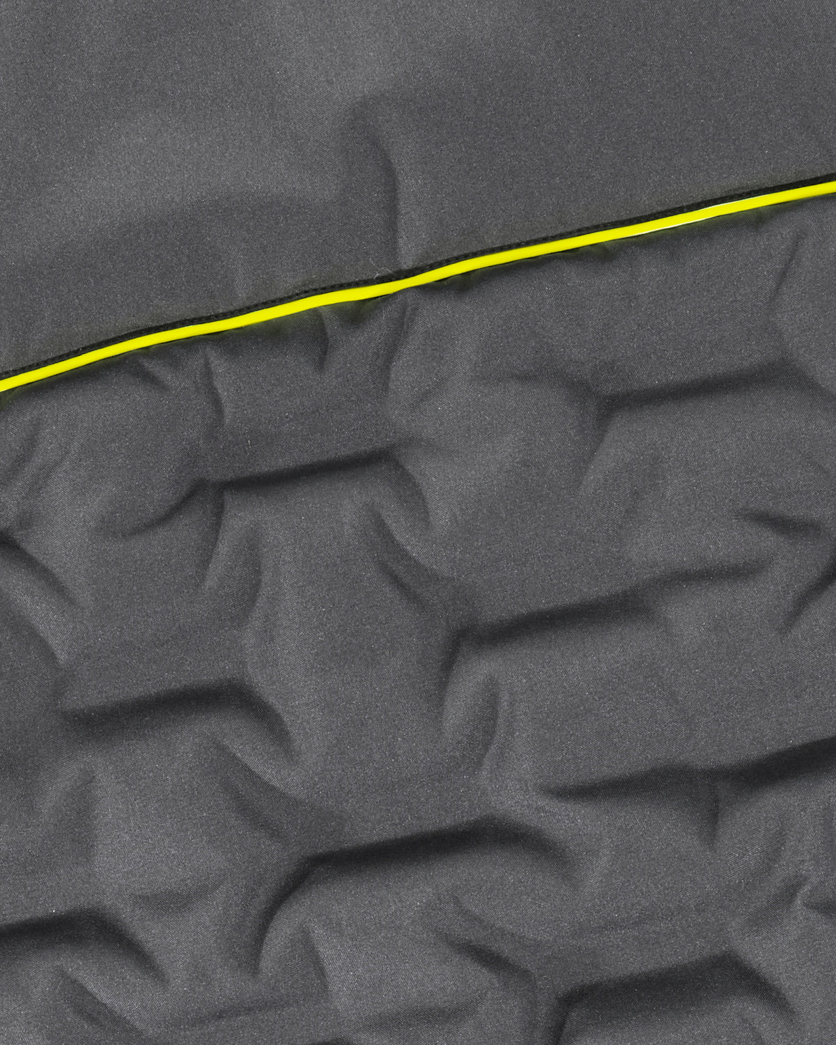 Close-up of dark gray quilted fabric with a bright yellow stitched line running diagonally across the surface.