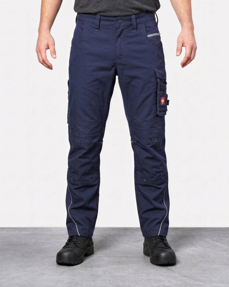 A person wearing navy blue cargo work pants with multiple utility pockets and black work boots, shown from the waist down against a light gray studio background.