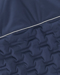 Close-up of a navy blue quilted fabric with a star-like pattern and a thin white piping detail running diagonally across the center.