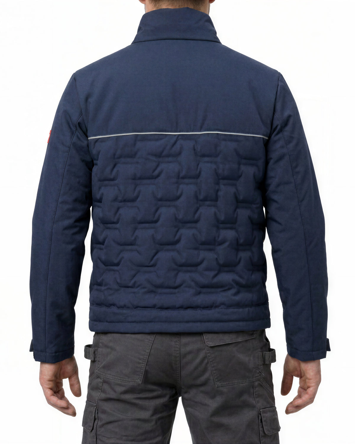 A man viewed from the back wearing a navy blue quilted jacket with a textured geometric pattern on the lower back and dark gray cargo pants, against a plain white background.