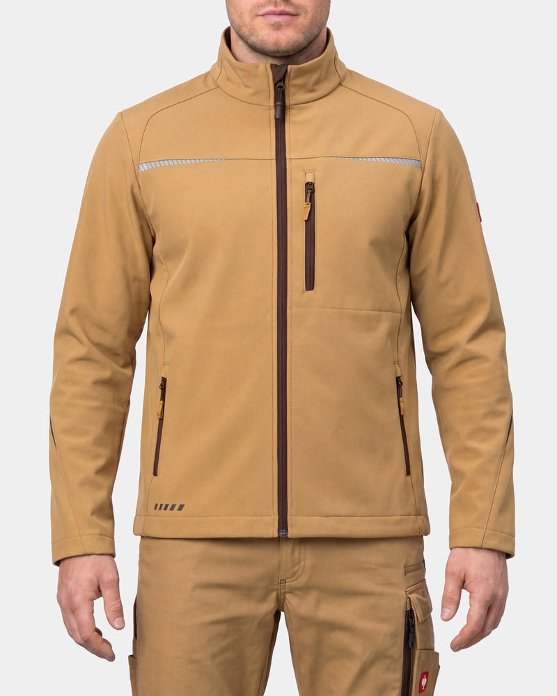 A man wearing a tan softshell jacket with a high collar, front zipper, and zippered pockets, paired with matching tan pants, against a light gray background.