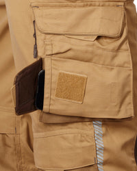 Close-up of a tan cargo bib showing a side utility pocket with a brown zippered card holder containing a black smartphone, alongside a tan Velcro patch.