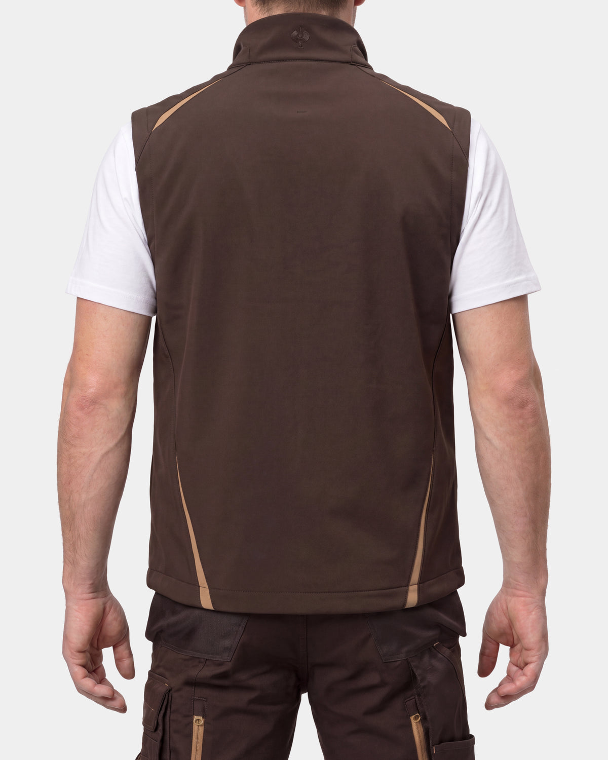 A man viewed from the back wearing a brown sleeveless zip vest over a white t-shirt and dark cargo pants, against a light gray studio background.