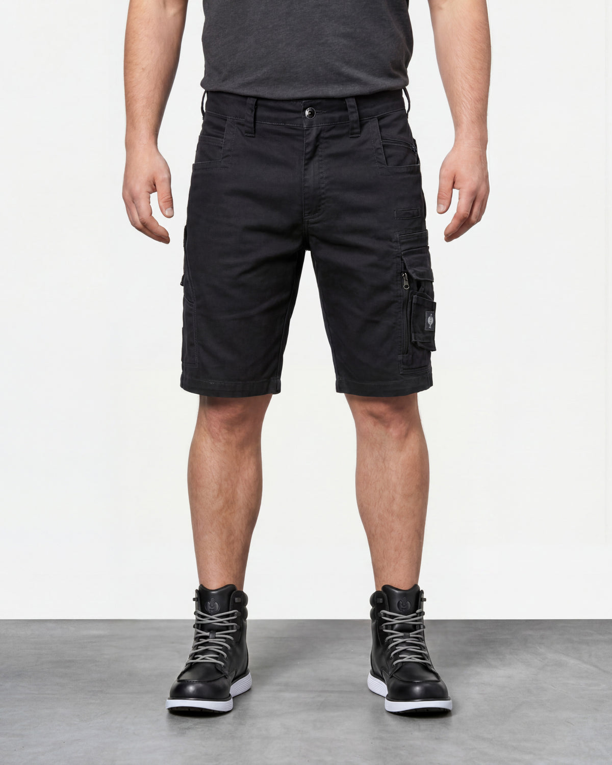 Model wearing Engelbert Strauss e.s. motion ten shorts in oxid black, showing the fit, length, waistband, and front pocket layout of the flexible work shorts designed for active movement.
