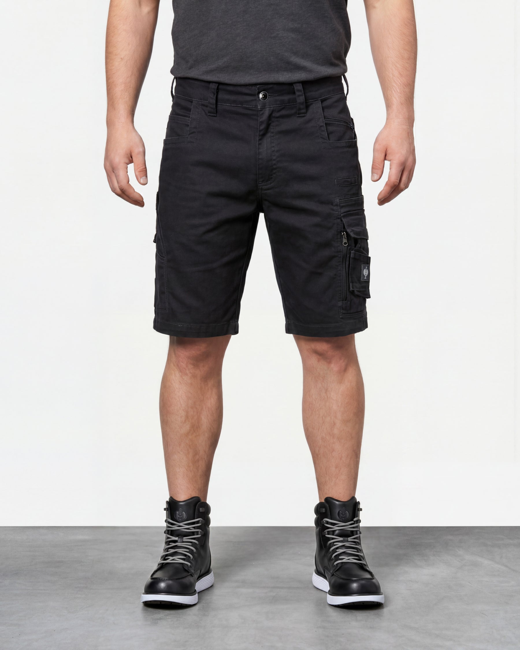 Model wearing Engelbert Strauss e.s. motion ten shorts in oxid black, showing the fit, length, waistband, and front pocket layout of the flexible work shorts designed for active movement.