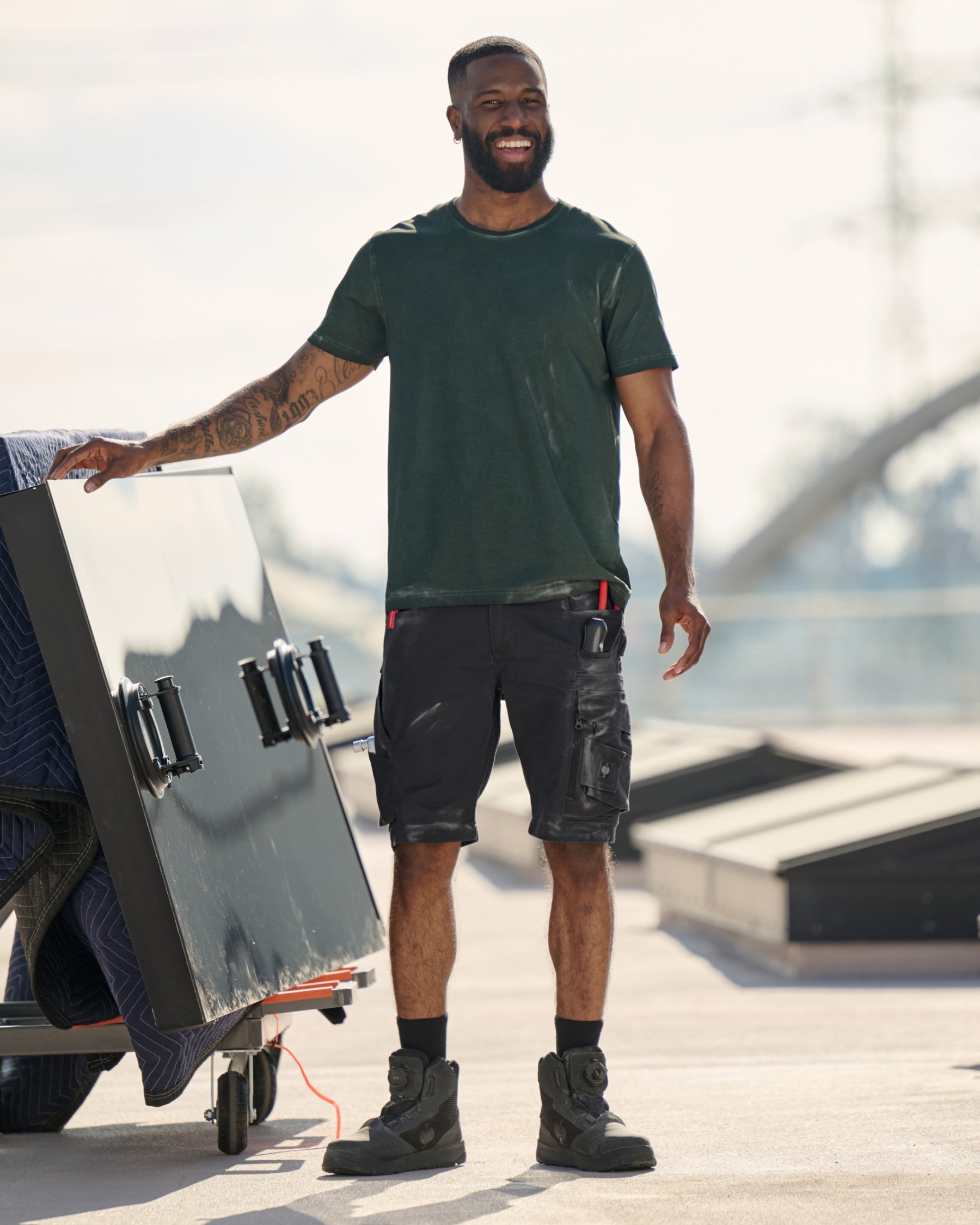 Engelbert Strauss e.s. motion ten shorts in oxid black in a lifestyle action view, highlighting the practical pocket access and durable workwear silhouette.