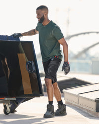 Engelbert Strauss e.s. motion ten shorts in oxid black in an outdoor-style lifestyle view, showing the shorts as part of a functional work outfit.