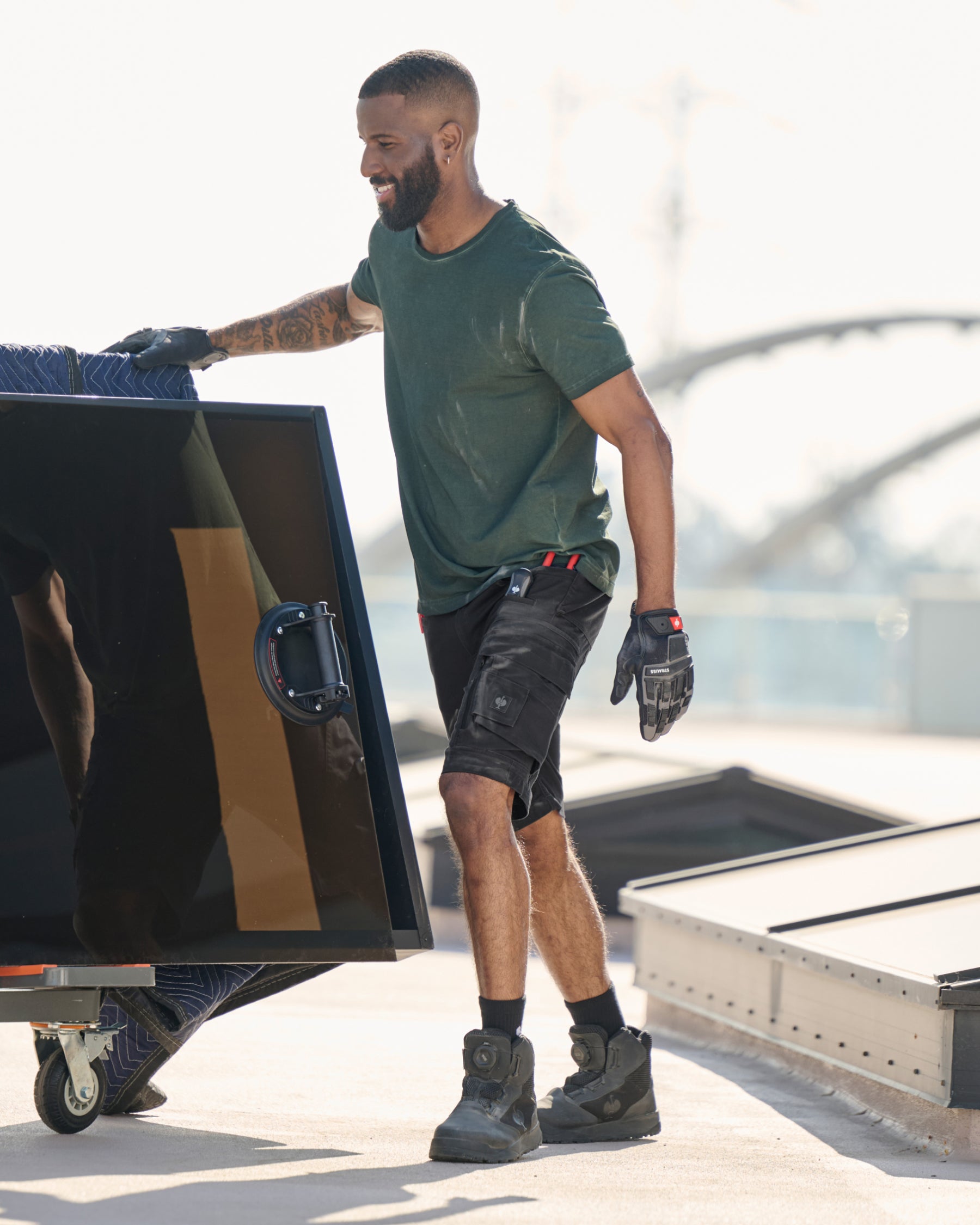 Engelbert Strauss e.s. motion ten shorts in oxid black in an outdoor-style lifestyle view, showing the shorts as part of a functional work outfit.