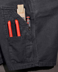Close-up detail of Engelbert Strauss e.s. iconic shorts in black, focusing on the utility pocket area, seams, and reinforced workwear construction.
