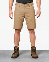 Model wearing Engelbert Strauss e.s. iconic shorts in almond brown, showing the fit, length, waistband, and front pocket layout of the classic work shorts with functional pocket details.